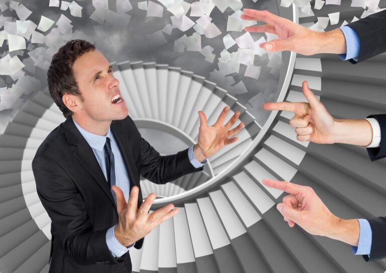 Hands blaming a frustrated businessman against paper sheets flying in background